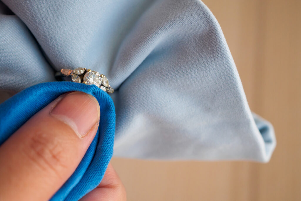 eweller hand polishing and cleaning jewelry diamond ring with micro fiber fabric