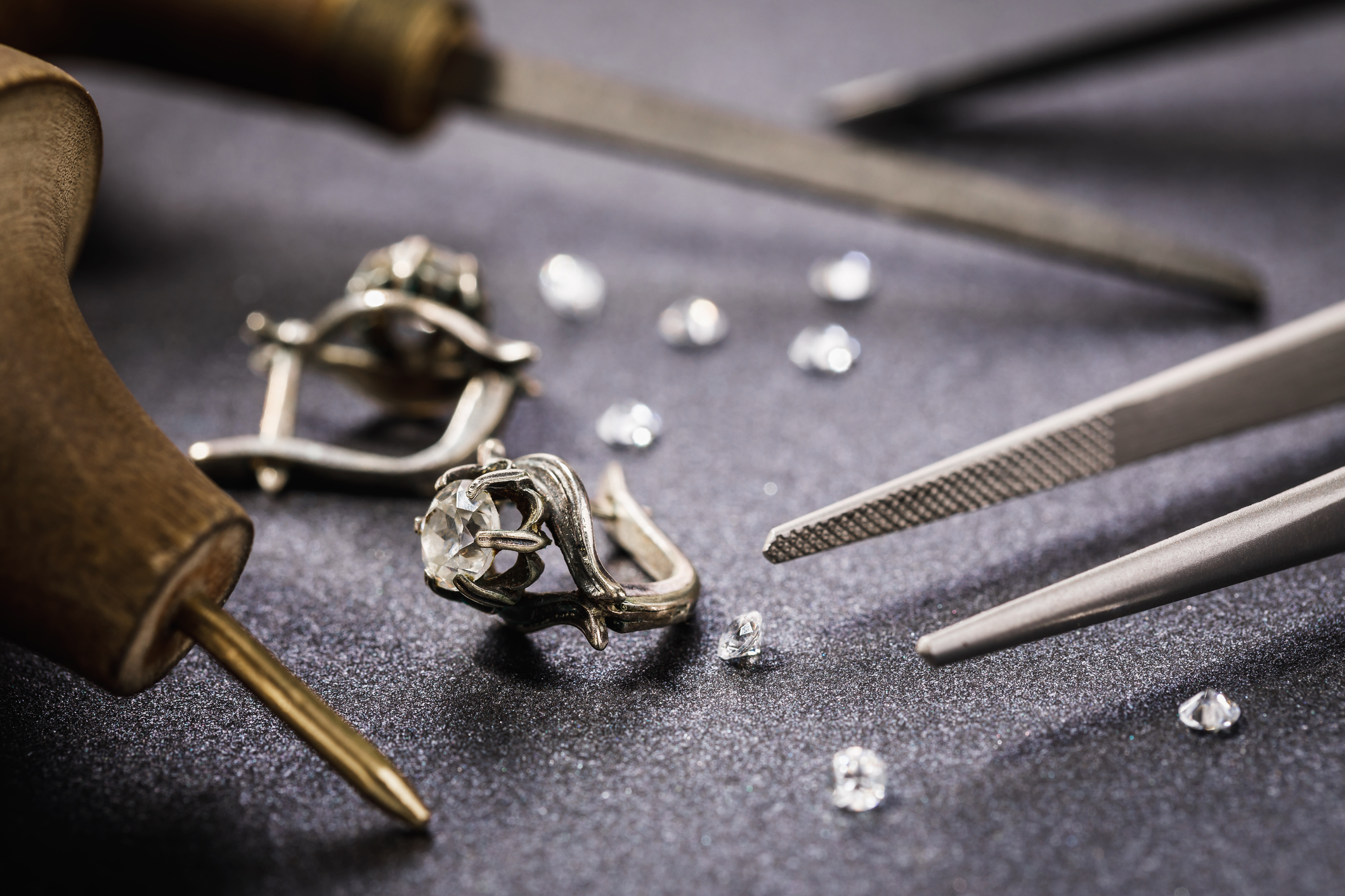 Earrings with a stone on the table, surrounded by jewelry repair tools