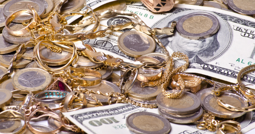 A pile of silver and gold jewelry on top of cash and coins