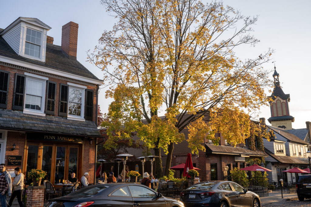 Doylestown, USA - November 5, 2023. People dining outdoor  at Penn Taproom in historic district of downtown Doylestown with people walking on sidewalk, Pennsylvania, USA